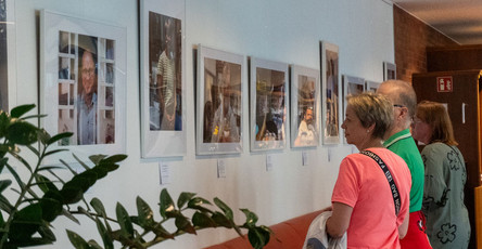 Besucher*innen betrachten gemeinsam die eindrucksvollen Bilder der Ausstellung „Friedrichshagener Kaleidoskop“ im Restaurant Vier Jahreszeiten der ProCurand Seniorenresidenz. Der Austausch über die Kunstwerke schafft eine anregende Atmosphäre.