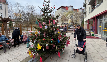 Ein glücklicher Senior in der ProCurand Seniorenresidenz bewundert den prachtvoll geschmückten Weihnachtsbaum.