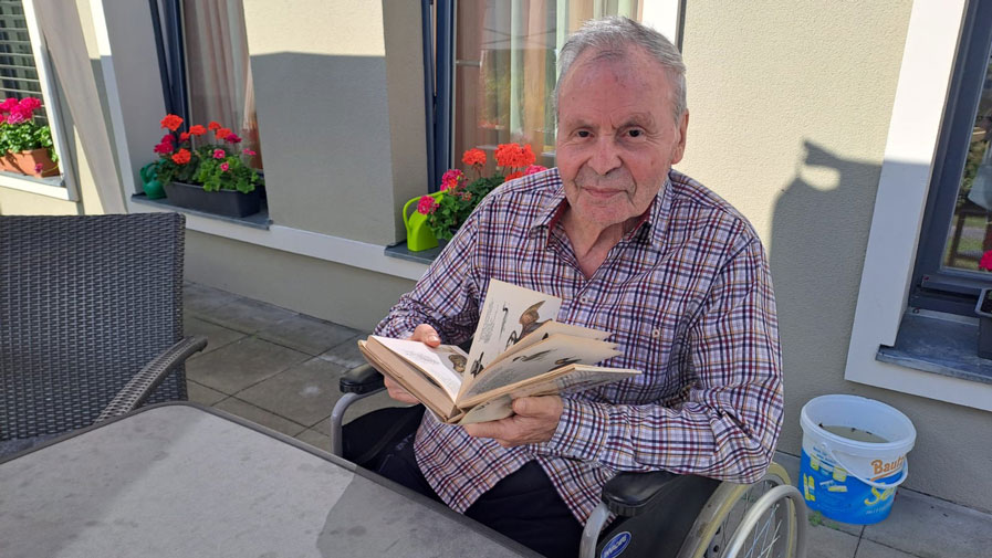 Ein Bewohner der ProCurand Seniorenresidenz Bölschestraße genießt eine wohlverdiente Pause im Garten und liest entspannt ein Buch.