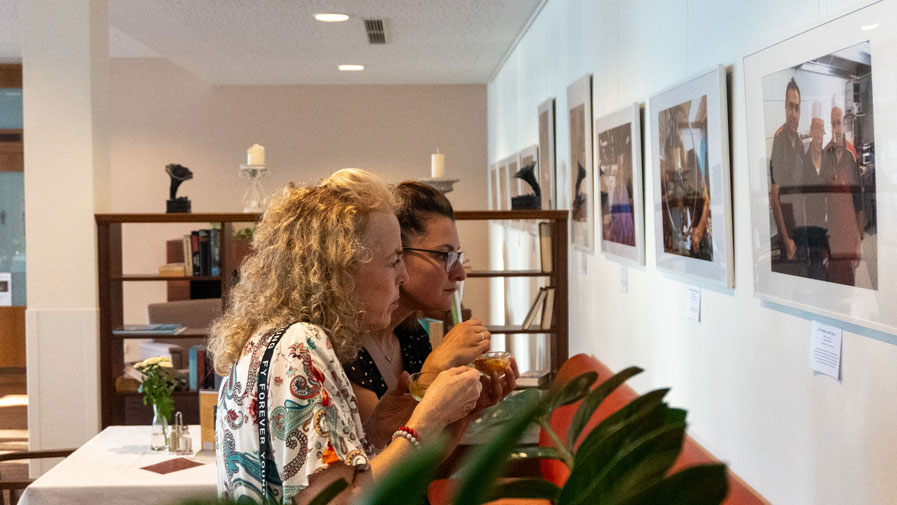 Besucher*innen betrachten konzentriert die eindrucksvollen Porträts der Ausstellung „Friedrichshagener Kaleidoskop“ im Restaurant Vier Jahreszeiten der ProCurand Seniorenresidenz.