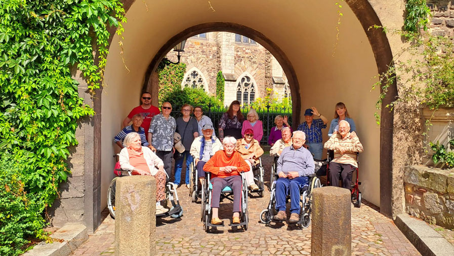 Die Bewohner*innen der ProCurand Seniorenresidenz Am Krökentor genießen das schöne Wetter vor dem Magdeburger Dom. Bei strahlendem Sonnenschein erfreuen sie sich an der beeindruckenden Kulisse und der gemeinsamen Zeit im Freien.