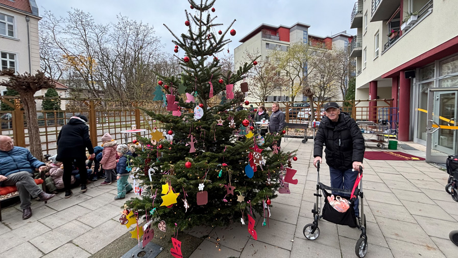 Ein glücklicher Senior in der ProCurand Seniorenresidenz bewundert den prachtvoll geschmückten Weihnachtsbaum.