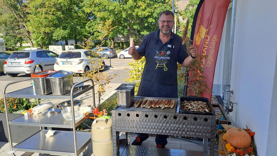 Haustechniker Jens Holzapfel grillt Würstchen für die Gäste beim ersten Sommerfest der ProCurand Tagespflege Strausberg und sorgt so für das leibliche Wohl der Feiernden.